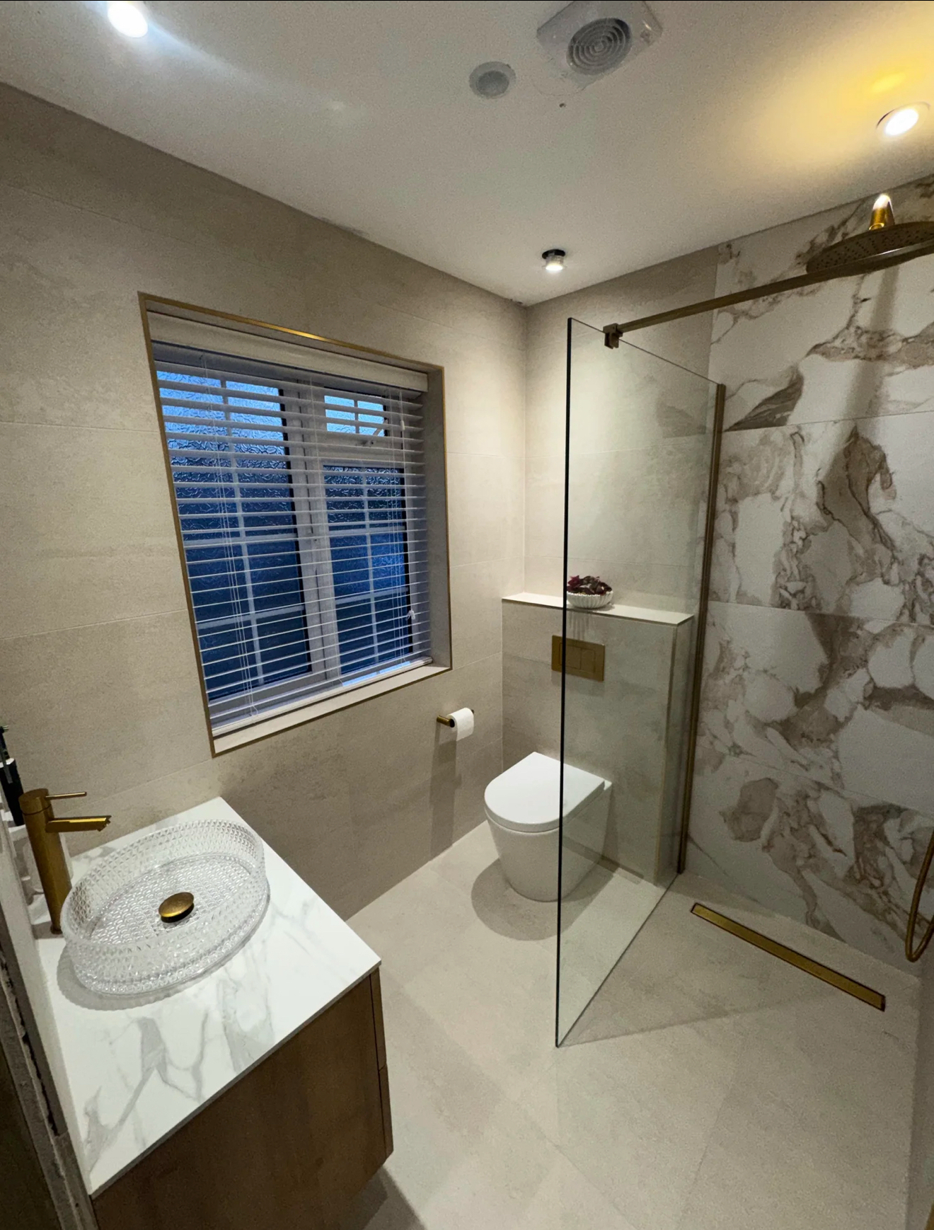 Elegant marble bathroom with clear glass walk-in shower, vessel basin, brass tap and window shutters — installed by Windsor Bathrooms & Plumbing in Windsor, Berkshire